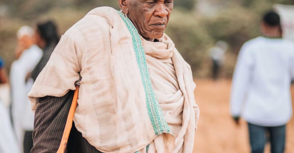 Walks - An old man with a cane walking through a field