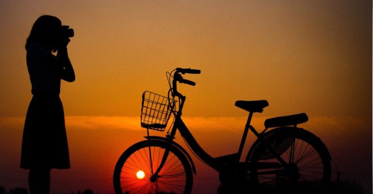 Tours - Silhouette of Woman Using Camera in Front of City Bicycle